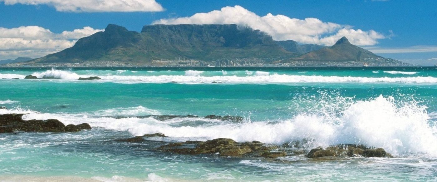 Table Mountain Cape Town seen across a turquoise ocean with crashing surf