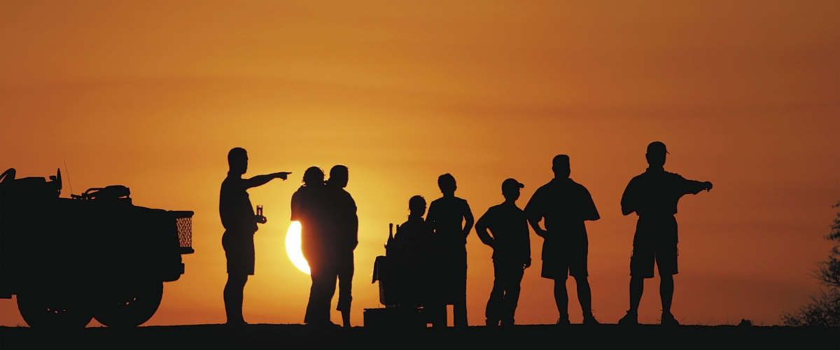 game drive sundowners with vehicle and people silhouetted against setting sun