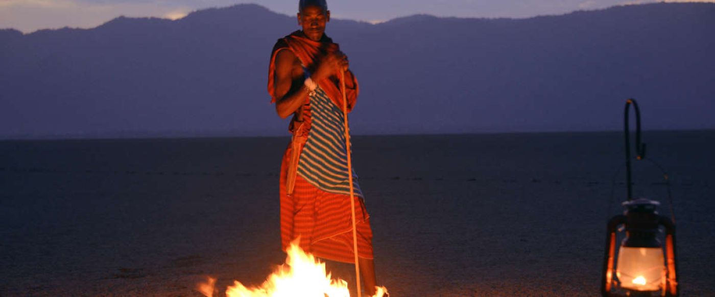 masai warrior standing next to camp fire in Tanzania 